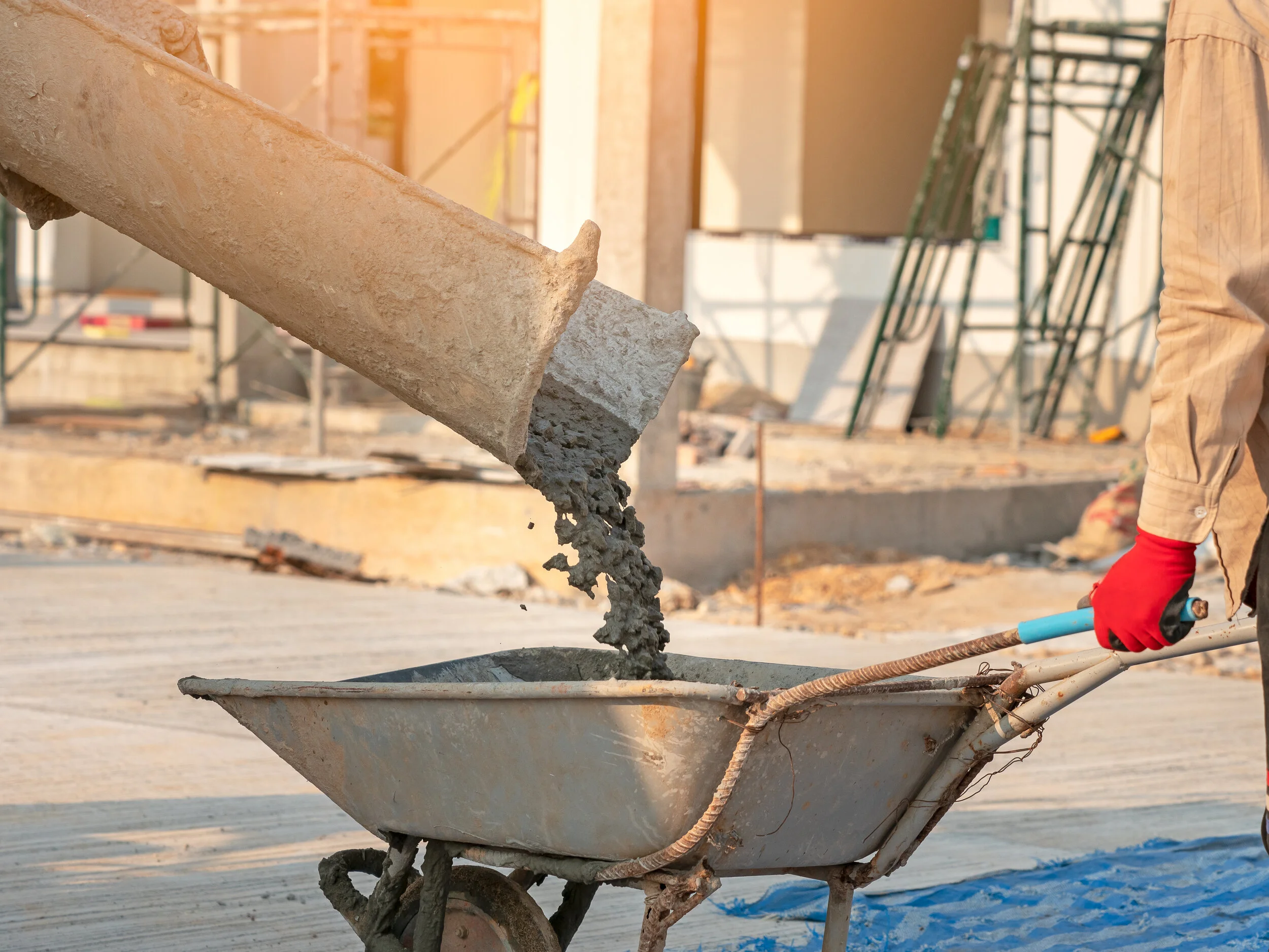 Concrete poured from a mixer chute into a wheelbarrow for an easy pour